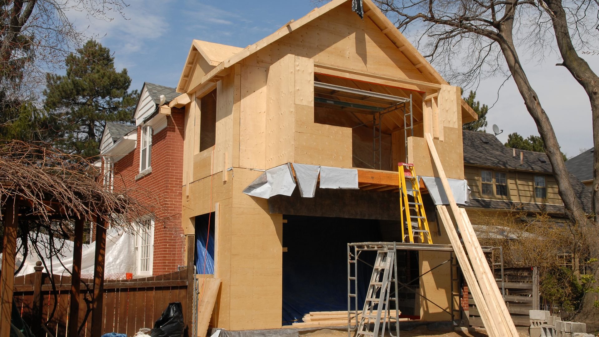 Home addition under construction with wooden framing and scaffolding