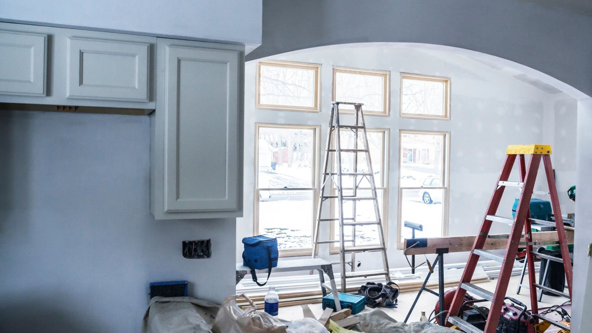 Home interior renovation with ladders, tools, and construction materials