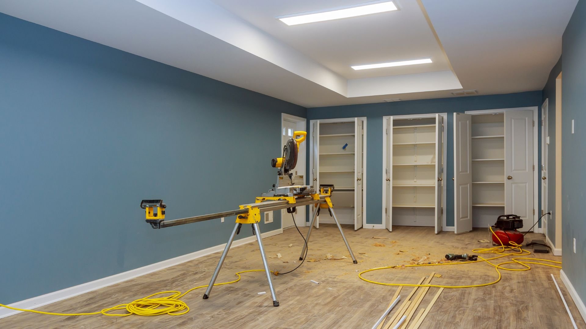 Room renovation with yellow tools, shelves, and blue walls in progress
