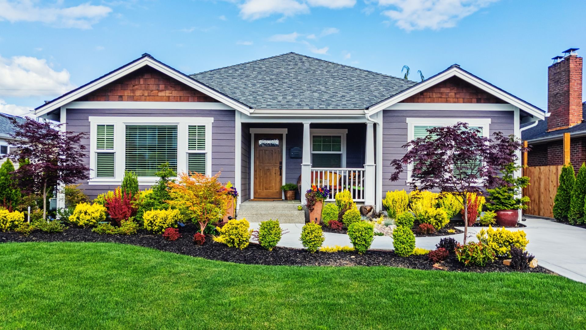 Craftsman-style house with colorful landscaped front yard on sunny day