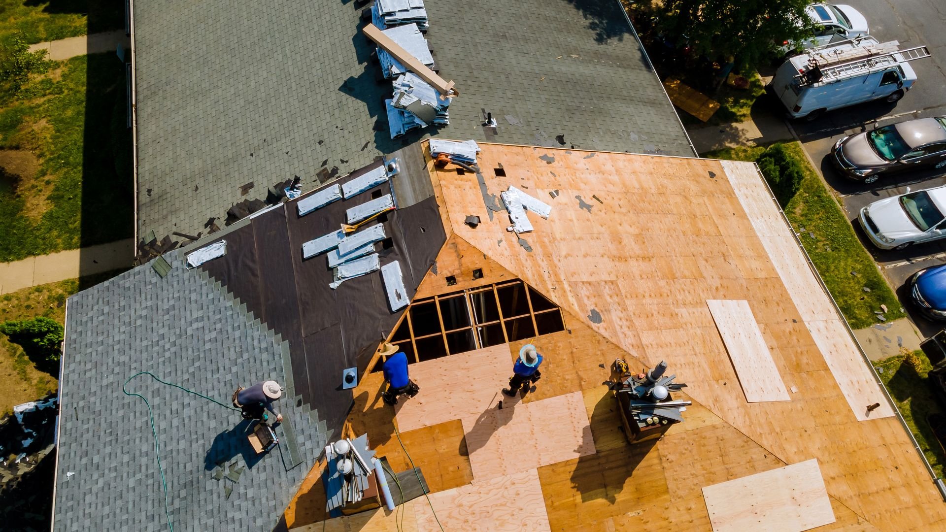 Aerial view of roofing contractors working on multiple house roofs