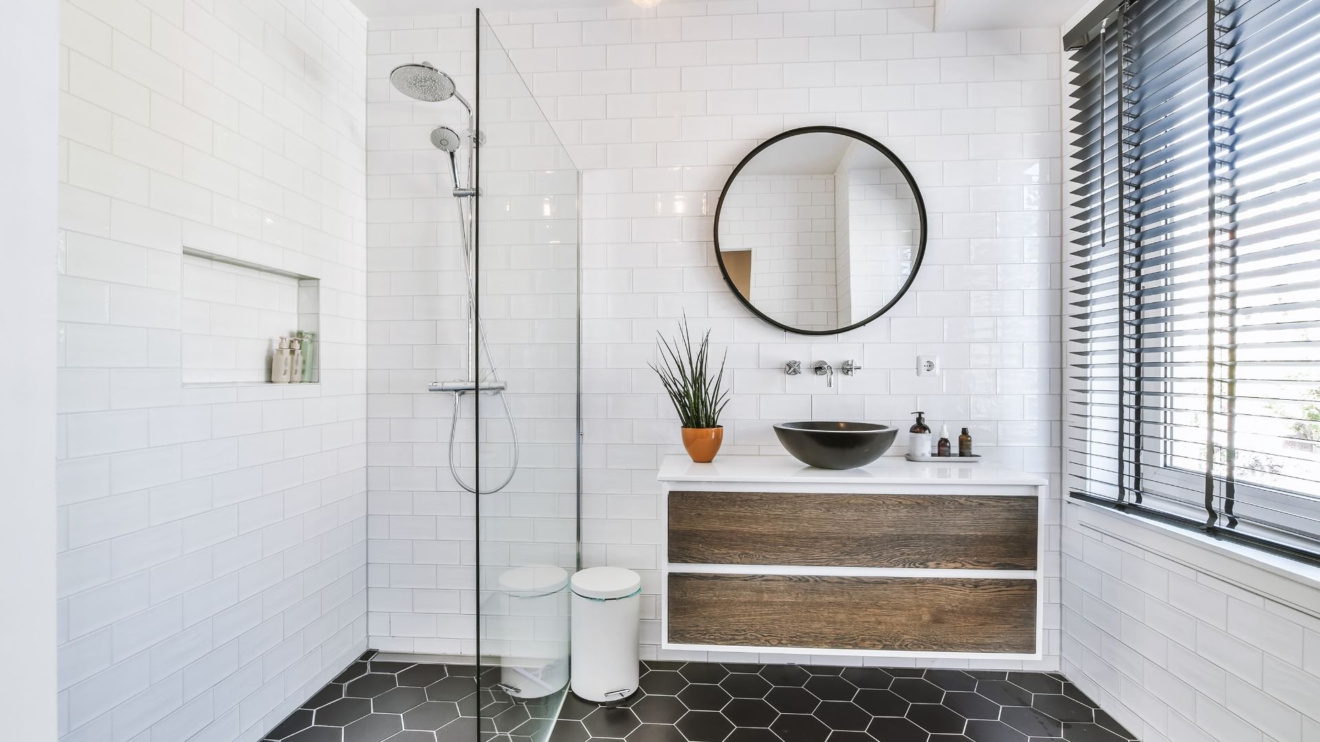 Modern white bathroom with walk-in shower, round mirror, and wooden vanity