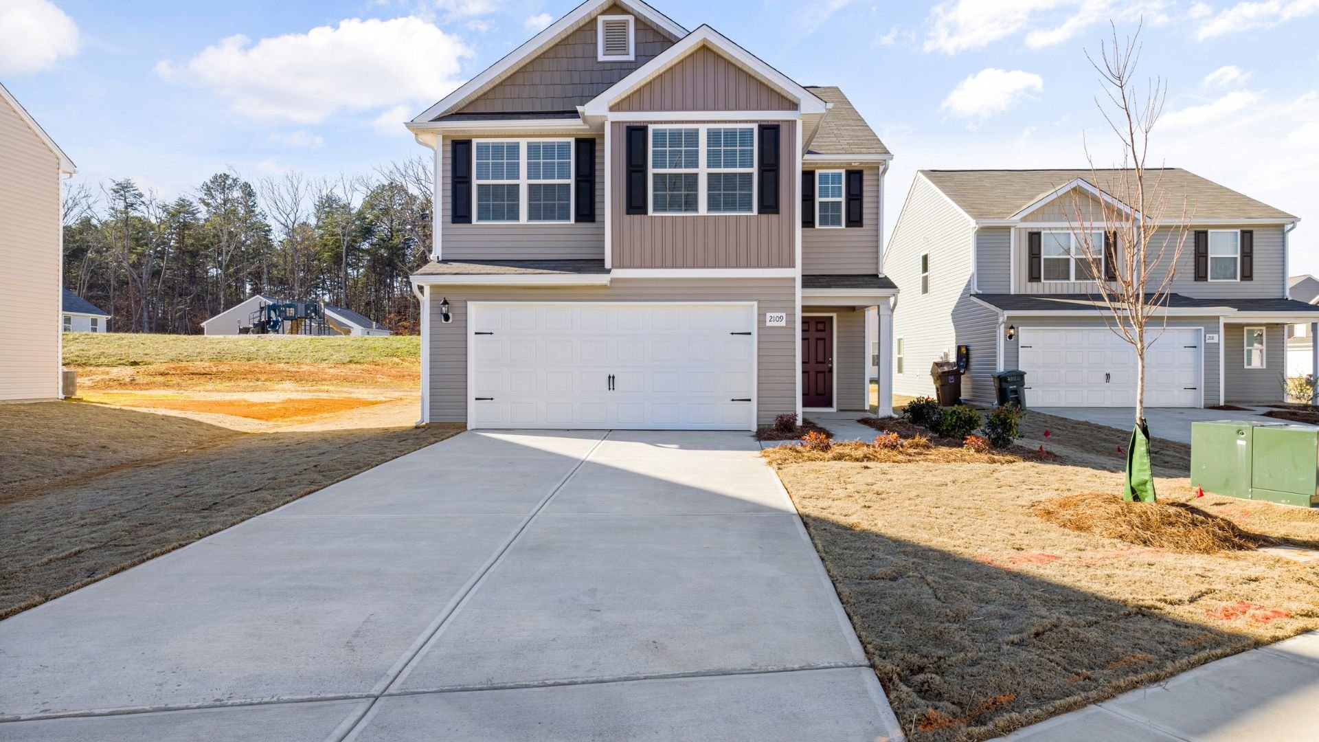 Two-story suburban house with white garage and beige siding on new development