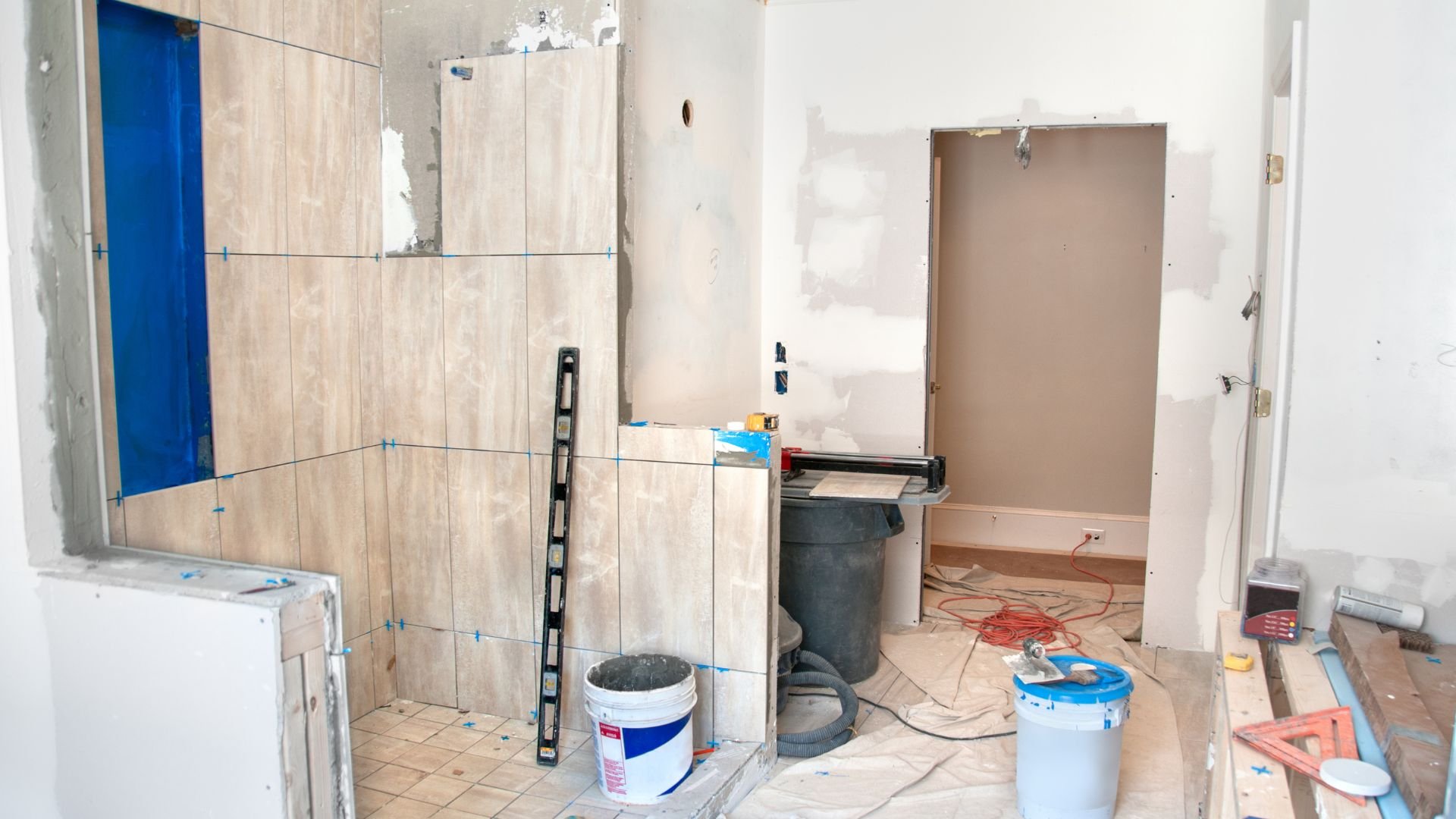 Bathroom renovation in progress with tiled walls and construction tools